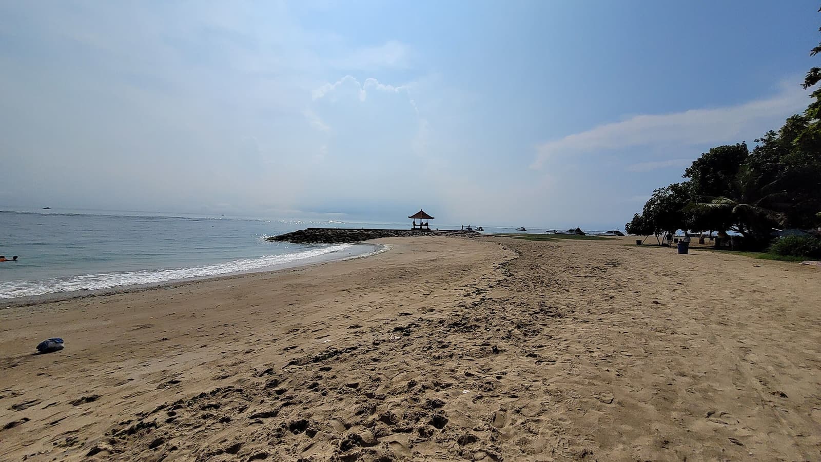 Le sable et l’eau calme et peu profonde de la plage de Sanur au matin
