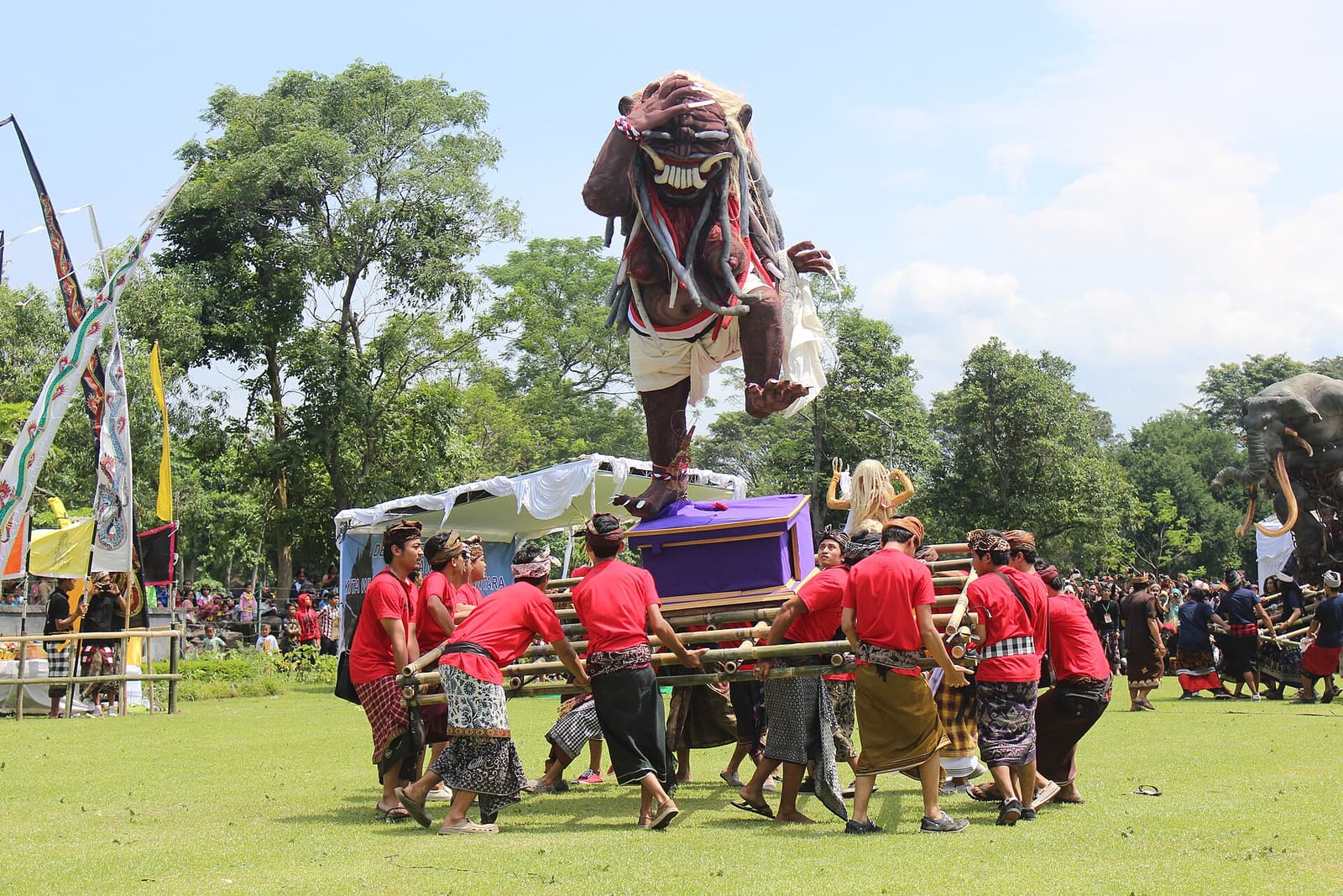 Des jeunes hommes portent une effigie ogoh-ogoh à travers un terrain à Bali