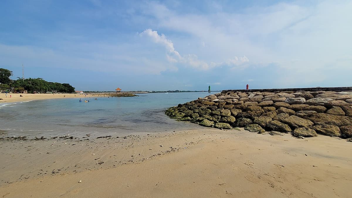 Sable, eau peu profonde et digue de pierre sur la plage de Sanur