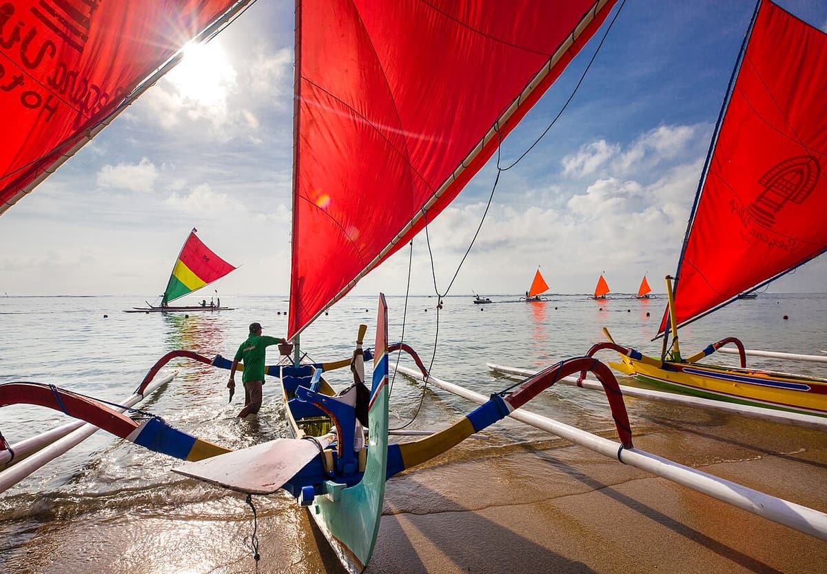 Pirogues à balancier traditionnelles jukung aux voiles rouges sur la plage de Sanur